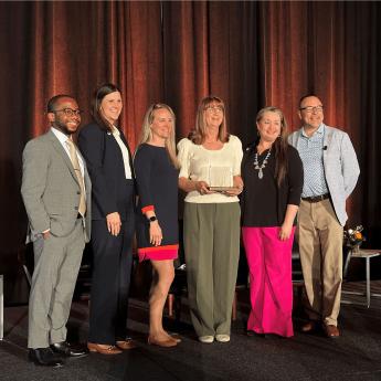 Amy Sapp holds the Patient Care Award trophy from NAPT while standing on stage with her colleagues from the UF Health Proton Therapy Institute.